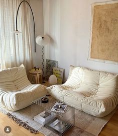 a living room with two white couches and a birdcage on the floor