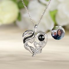 This is a mysterious necklace, personalized for the moment you love most on a projection necklace! Crafted in sterling silver, this endearing necklace representing a mother holding her child features a heart-shaped frame with a dangling projection stone and smaller stones embellishing the mother’s curvy hair. The baby is naughtily playing and the mother looks at her child patiently with love. The beautiful lines embody the gentle, graceful mother’s love. She always protects her naughty and innoc Mother's Day White Gold Birthstone Necklace Gift, Mother's Day Gift Birthstone Necklace, Mother's Day Gift Birthstone Necklace With Round Pendant, Mother's Day Gift Round Pendant Birthstone Necklace, Mother's Day Black Heart Pendant Necklace, Personalized White Gold Birthstone Necklace For Mother's Day, Elegant Silver Birthstone Necklace As Gift For Mom, Personalized White Gold Necklace For Mother's Day, Elegant Silver Birthstone Necklace For Personalized Gift