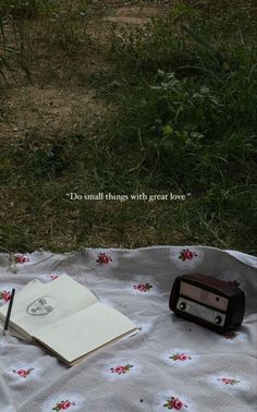 an old fashioned radio sitting on top of a blanket next to a book and pen