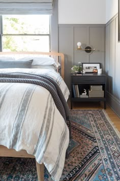 a bed sitting next to a window on top of a blue rug in a bedroom