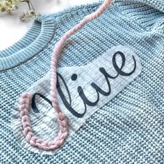 a blue sweater with the word live on it and a pink string hanging from it