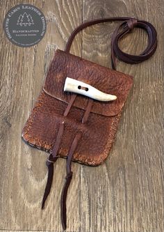 a brown leather pouch with a knife in it on a wooden table next to a cord