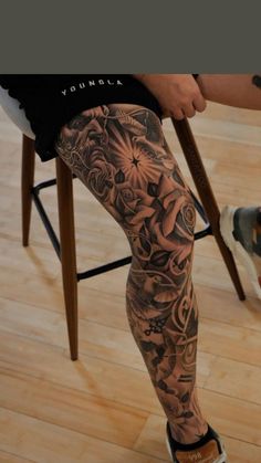 a person sitting in a chair with tattoos on their legs and leggings that have flowers all over them