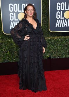 a woman in a black dress on the red carpet at an awards event with her hands on her hips