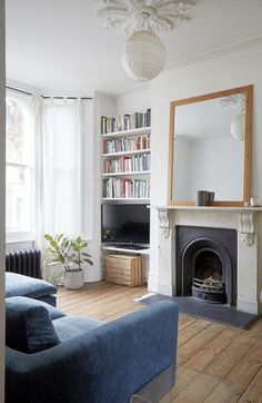 a living room filled with furniture and a fire place in front of a mirror on the wall