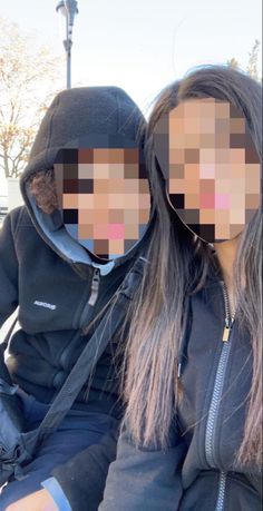 two people sitting next to each other with their faces covered by the same person's hoodie