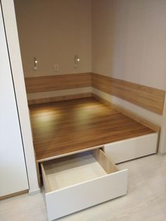 an empty room with wooden flooring and white drawers on the bottom half of it