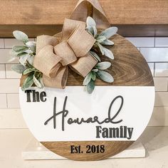 a wooden sign that says the howard family on it with a bow and greenery