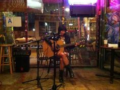 a woman sitting in front of a microphone while playing an acoustic guitar