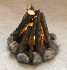 a fire pit made out of logs and rocks on the ground with a lit candle in it