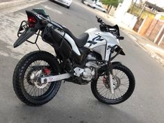 a white and black motorcycle parked on the side of a road next to a street