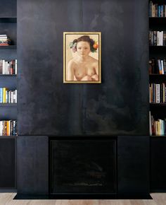 a painting hangs on the wall in front of a fireplace with bookshelves behind it