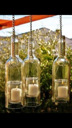 three glass bottles with candles hanging from them