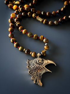 Express your freedom with the Eagle Tiger's Eye Necklace. This necklace is sure to elevate any stylish man's and women's look and the eagle symbolizes your strength and freedom. I combined tiger's eye stone beads with a high quality bronze , handmade and hand engraved Eagle Spirit Necklace represent freedom and power. Tiger's Eye traditionally is carried to protect the person against curses and ill intent. Tiger's eye brings self confidence to the wearer and resonates with both the root and sacr Bronze Spiritual Jewelry With Polished Beads, Blue Tiger Eye Stone, Eagle Pendant, Tigers Eye Necklace, Blue Tigers, Blue Tigers Eye, The Eagle, Tiger Eye Stone, Unique Necklace