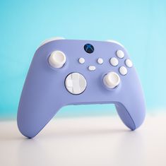 a close up of a purple controller on a white table with a blue wall in the background