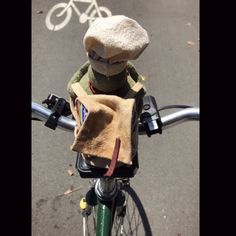 a stuffed animal sitting on the handle bars of a bicycle with a bag strapped to it