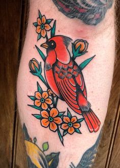 a red bird sitting on top of a branch with flowers