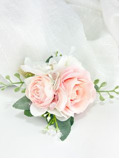 a bouquet of pink roses and greenery on a white cloth covered surface with water droplets