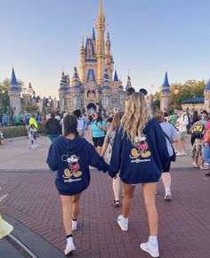 two girls in mickey mouse sweatshirts walking towards the castle