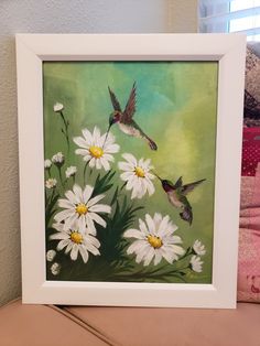 a painting of two hummingbirds flying over daisies