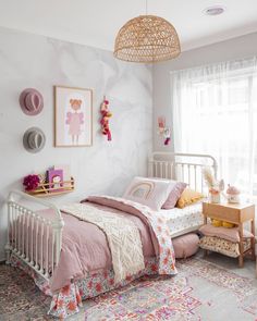 a child's bedroom with pink and white bedding, rugs and pictures on the wall