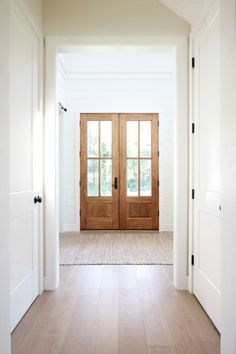 an empty hallway with two wooden doors and white walls