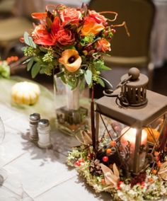 an arrangement of flowers in a vase on top of a table with candles and other decorations