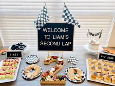 a table topped with lots of food and desserts next to a sign that says welcome to llama's second lap