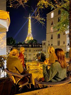 three women sitting at a table in front of the eiffel tower