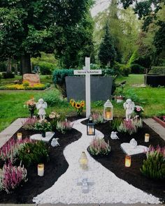 a cemetery with flowers and candles on the ground in front of a cross, surrounded by trees