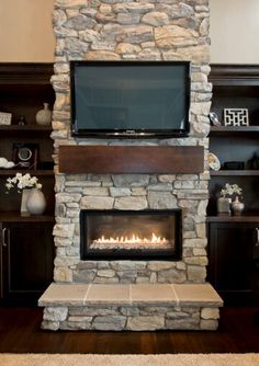 a living room with a stone fireplace and flat screen tv mounted on the wall above it