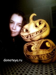 a woman standing next to two carved pumpkins