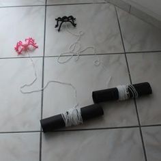 two black and white objects laying on the floor next to one pink piece of string