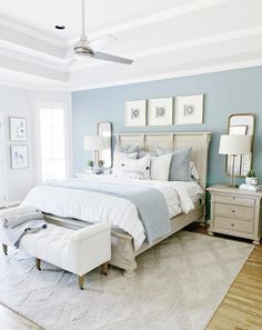 a bedroom with blue walls, white furniture and a large bed in the center of the room