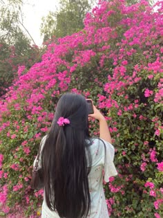 a woman standing in front of pink flowers