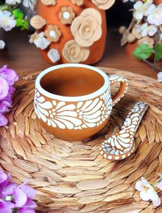 a cup and saucer sitting on top of a wicker tray next to flowers