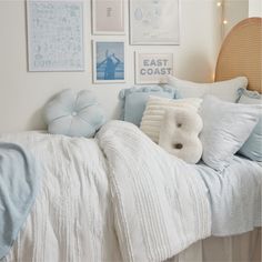 a bed with blue and white comforters in front of many pictures on the wall