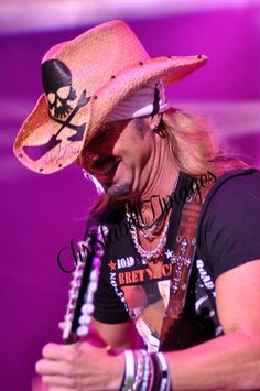 a man wearing a cowboy hat and holding a guitar in his right hand while singing into a microphone