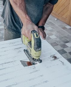 a man sanding wood with a power tool on it's side and nails in the middle