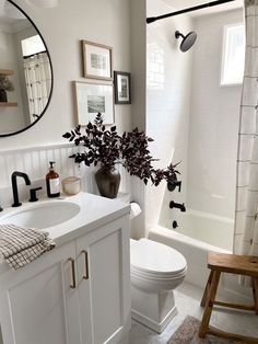 a bathroom with a white toilet sitting next to a bath tub under a round mirror