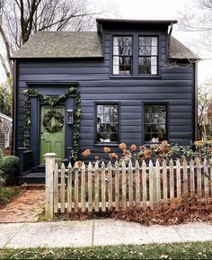 a house with a picket fence in front of it and flowers growing on the side