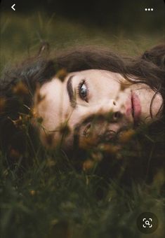 a woman laying in the grass with her eyes open