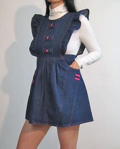 Vintage '80s denim pinafore dress. 100% cotton denim.  Ruffles at sides of bodice.  Attached bow detailing at front + pockets.  2 side pockets.  Pleated empire waist with elasticized sides.  Buttons down back bodice. Unlined.  *Best suited to a petite gal. DETAILS-----> Label:  Longstreet Era: '80s Fabric: 100% cotton denim MEASUREMENTS-----> Tag size:  marked a size 10 (junior's sizing) - should suit a size xxs - xs/small *note: the waist has to fit over either the hips or bust to get dress on Bust:  open (best for 34B or smaller) Empire waist:  13.75 - 15.25" max Hips: free  Length:  30.5" CONDITION-----> In excellent vintage condition. No flaws to note.  *Model is a size xs/s with measurements (bust, waist, hips): 34", 26", 35 Denim Ruffles, Denim Pinafore Dress, Denim Pinafore, 80s Denim, Indigo Denim, Bow Dress, Apron Dress, Dark Indigo, Pinafore Dress