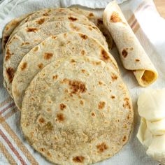 four tortillas are sitting on a towel next to some sliced bananas and butter