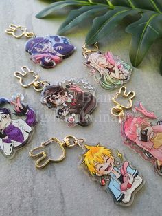 anime keychains with cartoon characters on them sitting next to a plant and leaves