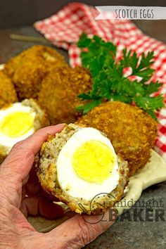 a person holding an egg in between two pieces of breaded food on a plate