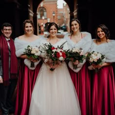 a group of women standing next to each other wearing red dresses and fur stoles