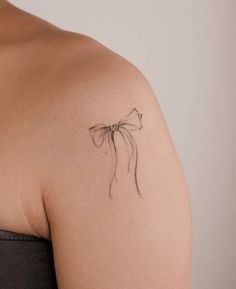 a woman with a tattoo on her shoulder that has a bow in the middle of it