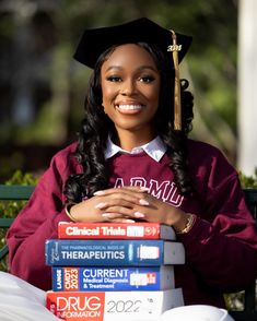 a woman sitting on a bench wearing a graduation cap and gown with her arms crossed