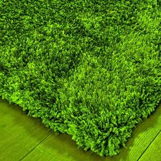 a green area rug on top of a wooden floor